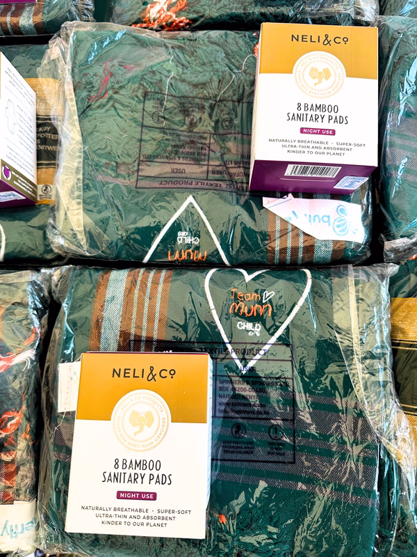 Box of Neli & Co bamboo sanitary pads on top of Team Mum branded lesos