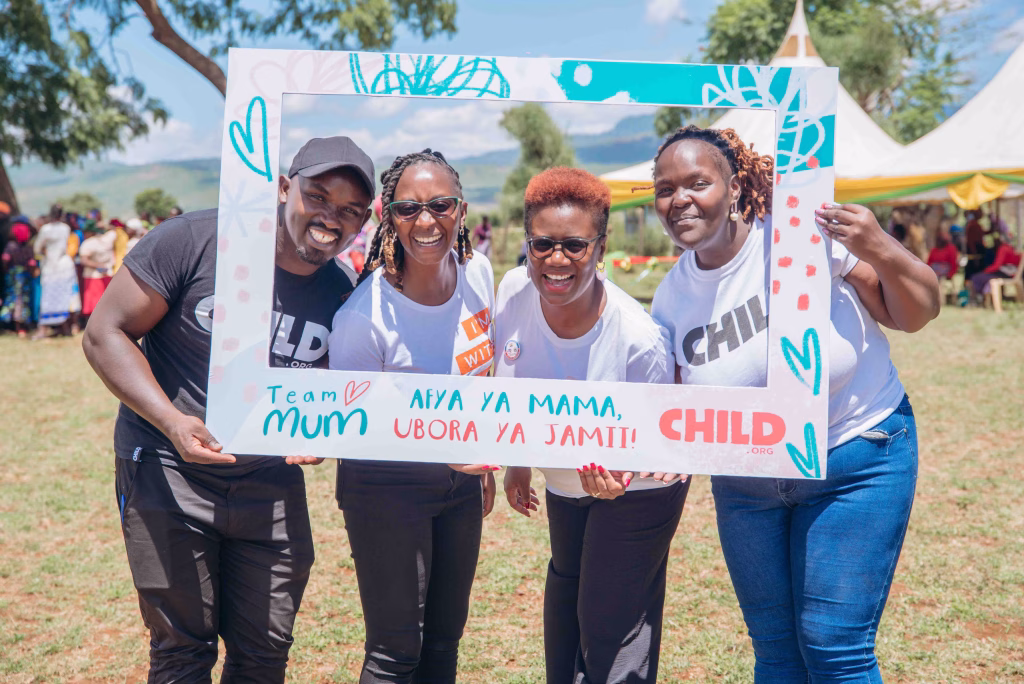 Cherio Onacha and the Child.org team holding a Team Mum photo frame at a community event in Kenya